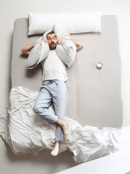 Ovanifrån foto av ung man sover i en stor vit säng — Stockfoto