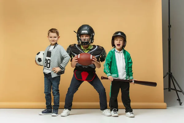 Trzy szczęśliwe dzieci wykazują różne sport. Studio moda koncepcja. Koncepcja emocje. — Zdjęcie stockowe