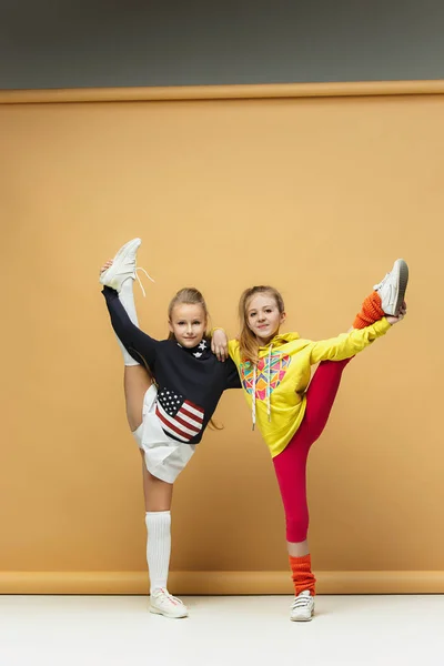 Zwei glückliche Kinder zeigen unterschiedliche Sportarten. Studio-Mode-Konzept. Emotionen-Konzept. — Stockfoto