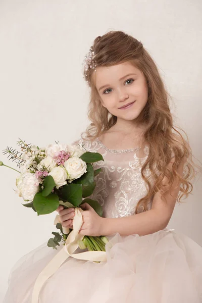 Маленька красива дівчинка з квітами, одягнена у весільні сукні — стокове фото