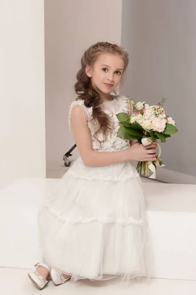 Little pretty girl with flowers dressed in wedding dresses — Stock Photo, Image