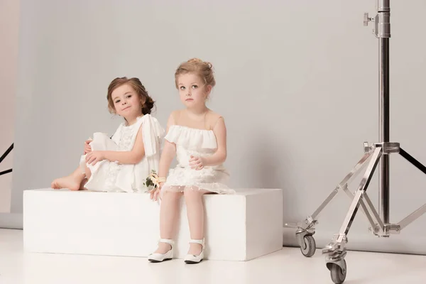 Маленькие красивые девочки с цветами, одетые в свадебные платья — стоковое фото