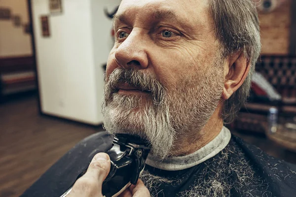 Nahaufnahme von der Seite Porträt von schönen älteren bärtigen kaukasischen Mann immer Bartpflege in modernen Friseursalon. — Stockfoto