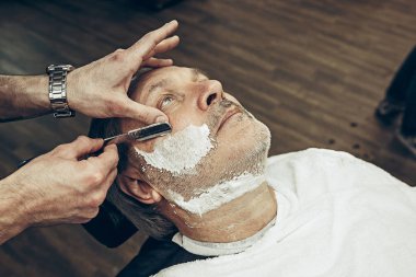 Yakın çekim yan üstten görünüm yakışıklı kıdemli beyaz adam modern berber sakal bakım alma sakallı.