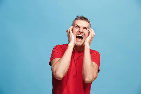 El joven hombre enojado emocional gritando en el fondo del estudio azul — Foto de Stock