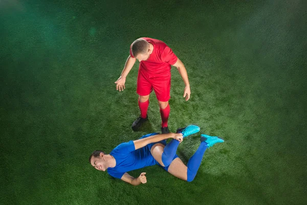 Jogador de futebol masculino sofrendo de lesão na perna no campo verde do futebol — Fotografia de Stock
