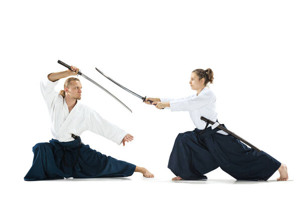 Мужчина и женщина сражаются и тренируют айкидо на белом фоне студии
