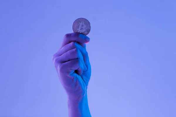 Mão masculina com bitcoin dourado no fundo azul — Fotografia de Stock