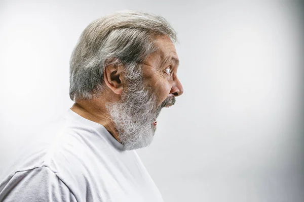 Старший эмоциональный сердитый мужчина кричит на белом фоне студии — стоковое фото