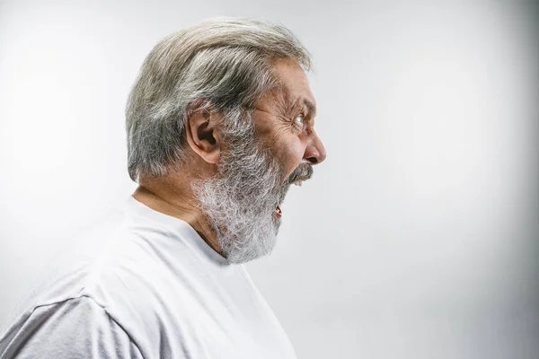 Старший эмоциональный сердитый мужчина кричит на белом фоне студии — стоковое фото