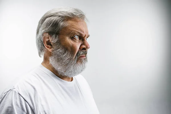 Älterer Mann mit angeekeltem Gesichtsausdruck, der etwas auf Weiß abstößt — Stockfoto