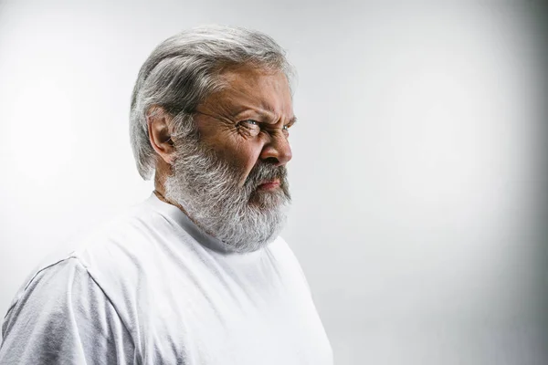 Älterer Mann mit angeekeltem Gesichtsausdruck, der etwas auf Weiß abstößt — Stockfoto