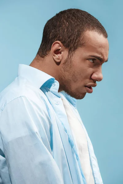 Молодий емоційно розлючений чоловік на синьому фоні студії — стокове фото