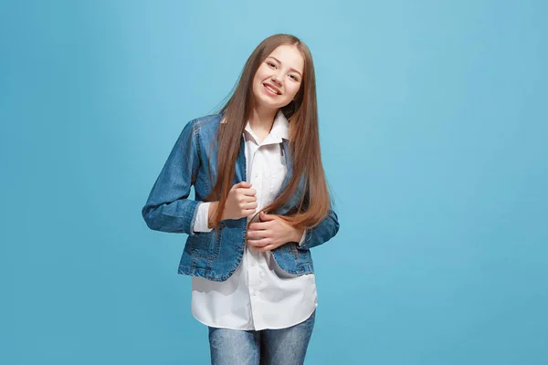 De gelukkige tiener meisje permanent en glimlachend tegen blauwe achtergrond. — Stockfoto