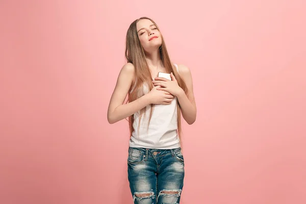 Das fröhliche Teenager-Mädchen, das vor rosa Hintergrund steht und lächelt. — Stockfoto