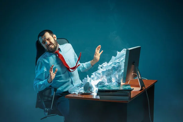 Молодий підкреслений красивий бізнесмен працює за столом в сучасному офісі кричить на екрані ноутбука і сердиться на спам — стокове фото