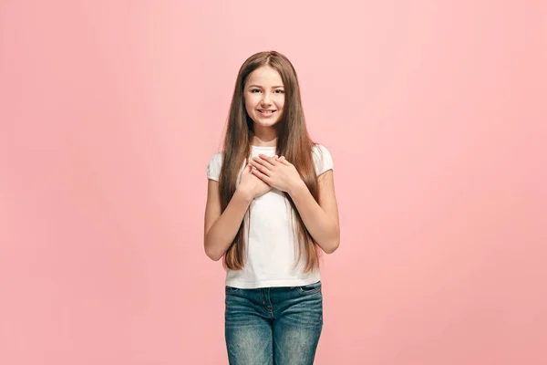 Das fröhliche Teenager-Mädchen, das vor rosa Hintergrund steht und lächelt. — Stockfoto