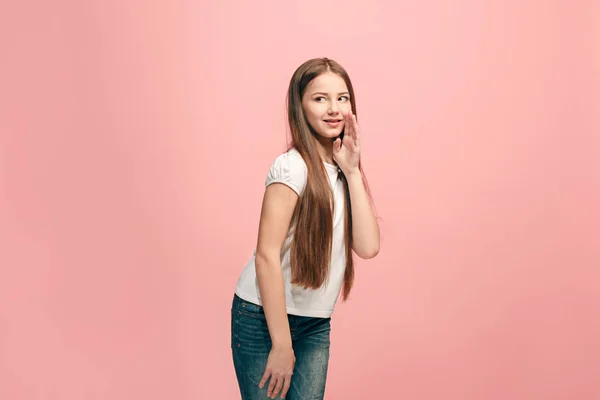 A jovem adolescente sussurrando um segredo atrás de sua mão sobre fundo rosa — Fotografia de Stock