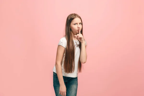 Молодая девушка-подросток шепчет тайну за своей рукой на розовом фоне — стоковое фото