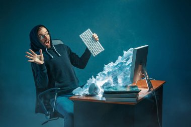 Genç yakışıklı işadamı dizüstü bilgisayar ekranında bağırmak ve spam hakkında kızgın modern ofis masasında çalışan vurguladı