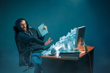 Genç yakışıklı işadamı dizüstü bilgisayar ekranında bağırmak ve spam hakkında kızgın modern ofis masasında çalışan vurguladı