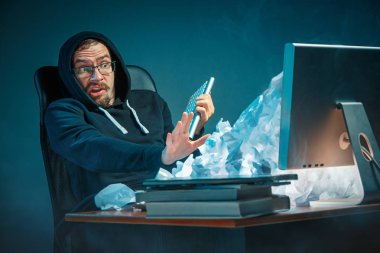 Genç yakışıklı işadamı dizüstü bilgisayar ekranında bağırmak ve spam hakkında kızgın modern ofis masasında çalışan vurguladı