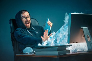 Genç yakışıklı işadamı dizüstü bilgisayar ekranında bağırmak ve spam hakkında kızgın modern ofis masasında çalışan vurguladı
