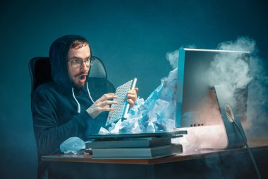 Genç yakışıklı işadamı dizüstü bilgisayar ekranında bağırmak ve spam hakkında kızgın modern ofis masasında çalışan vurguladı