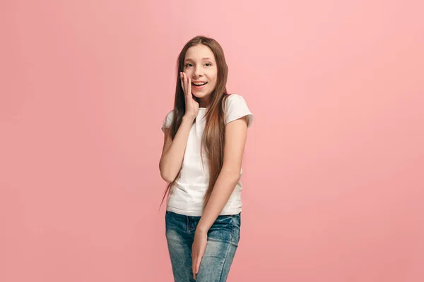 De jonge tiener meisje fluisteren van een geheim achter haar hand op roze achtergrond — Stockfoto