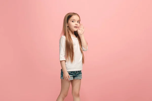 Das junge Teenie-Mädchen flüstert ein Geheimnis hinter ihrer Hand über rosa Hintergrund — Stockfoto