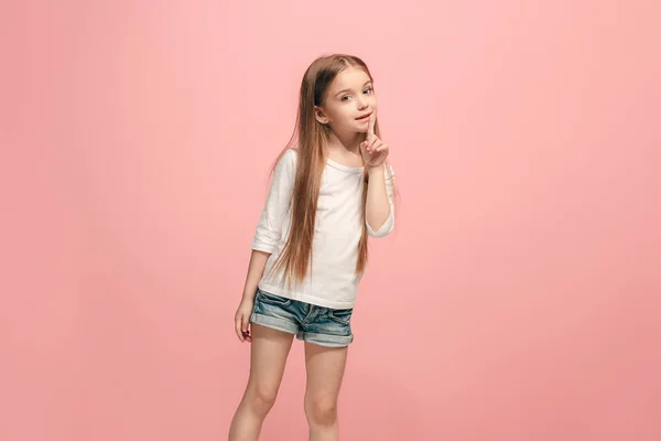 De jonge tiener meisje fluisteren van een geheim achter haar hand op roze achtergrond — Stockfoto