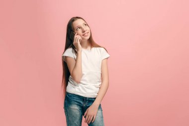 Mutlu genç kız ayakta ve pembe arka plan üzerinde gülümseyen.