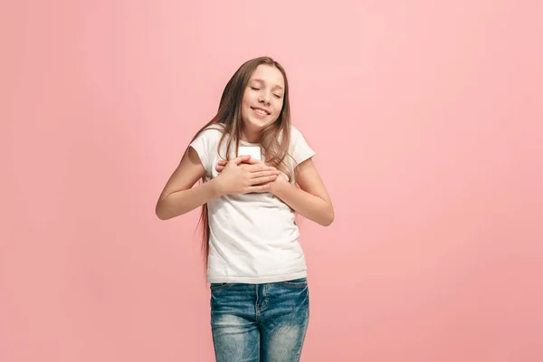 De gelukkige tiener meisje met telefoon permanent en glimlachend tegen roze achtergrond. — Stockfoto