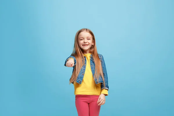 La chica adolescente feliz que apunta a usted, media longitud primer plano retrato sobre fondo azul . — Foto de Stock