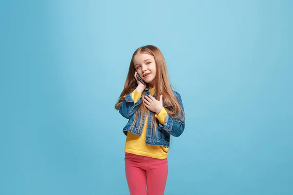 Ευτυχής έφηβος κορίτσι στέκεται και χαμογελαστός σε μπλε φόντο. — Φωτογραφία Αρχείου