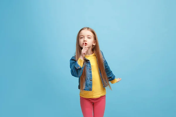Den unga tonåring flicka viskar en hemlighet bakom hennes hand över Blå bakgrund — Stockfoto