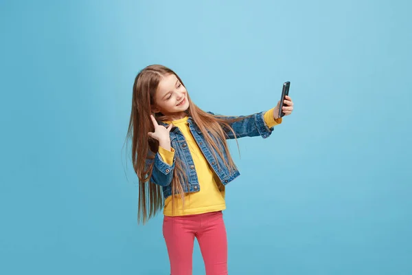 La chica adolescente feliz de pie y sonriendo contra el fondo azul . —  Fotos de Stock