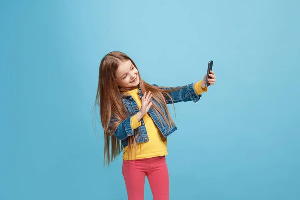 La chica adolescente feliz de pie y sonriendo contra el fondo azul . — Foto de Stock