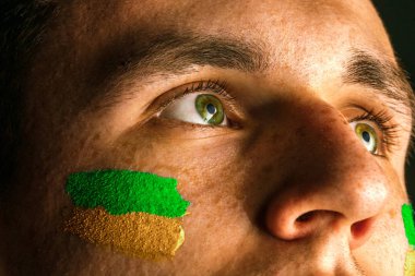 Portrait of a man with the flag of the Brazil painted on him face. clipart