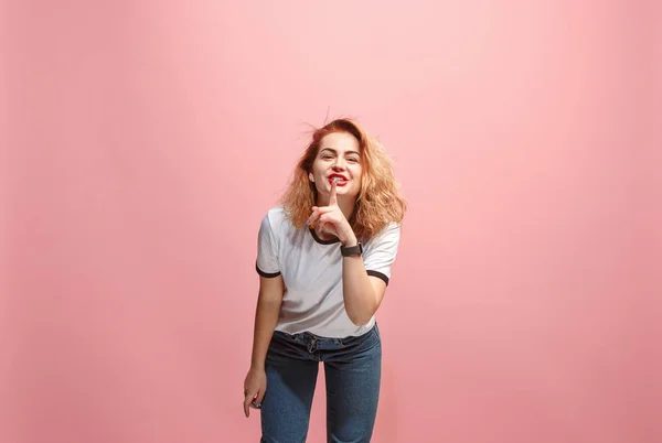 The young woman whispering a secret behind her hand over pink background — Stock Photo, Image