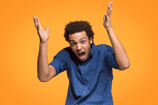 Den unge känslomässiga arga mannen skrek på orange studio bakgrund — Stockfoto