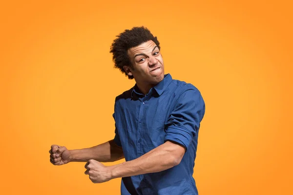 El joven hombre enojado emocional gritando en fondo de estudio naranja —  Fotos de Stock