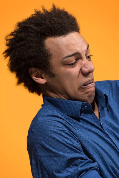 Lasst mich nachdenken. Nachdenklicher Mann mit nachdenklichem Gesichtsausdruck trifft Wahl vor orangefarbenem Hintergrund — Stockfoto