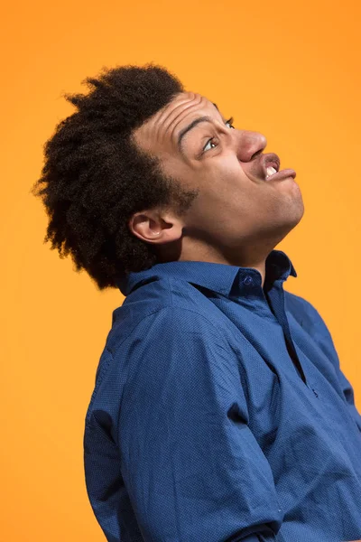 The young emotional angry man screaming on orange studio background — Stock Photo, Image