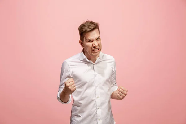 Der junge emotionale wütende Mann schreit auf rosa Studiohintergrund — Stockfoto