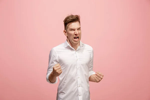 El joven hombre enojado emocional gritando en el fondo del estudio rosa —  Fotos de Stock