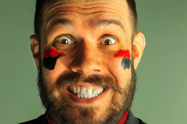 Portrait of a man with the flag of the Germany painted on him face.