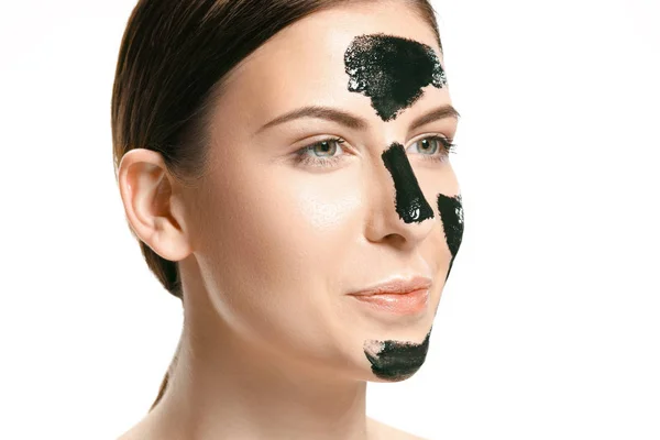 Jonge mooie vrouw een masker voor het gezicht van de therapeutische zwarte modder toe te passen. Spa-behandeling — Stockfoto