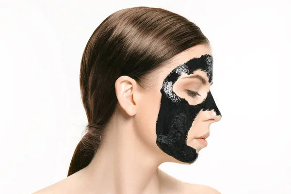 Jonge mooie vrouw een masker voor het gezicht van de therapeutische zwarte modder toe te passen. Spa-behandeling — Stockfoto