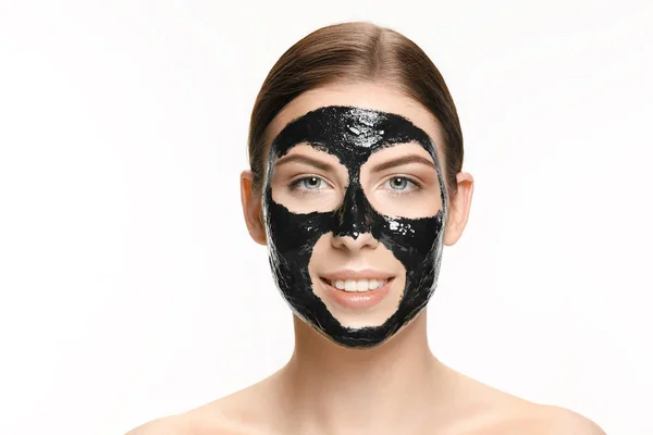 Junge schöne Frau, die eine Maske für das Gesicht des therapeutischen schwarzen Schlammes aufträgt. Wellness-Behandlung — Stockfoto